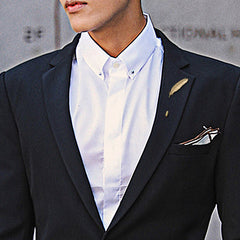 Gold feather lapel pin against a white background