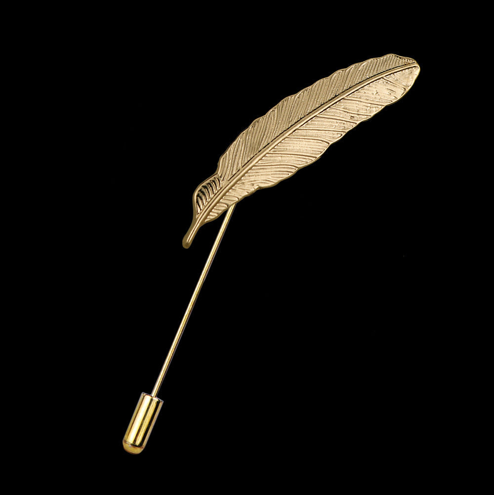 Silver feather lapel pin displayed on fabric