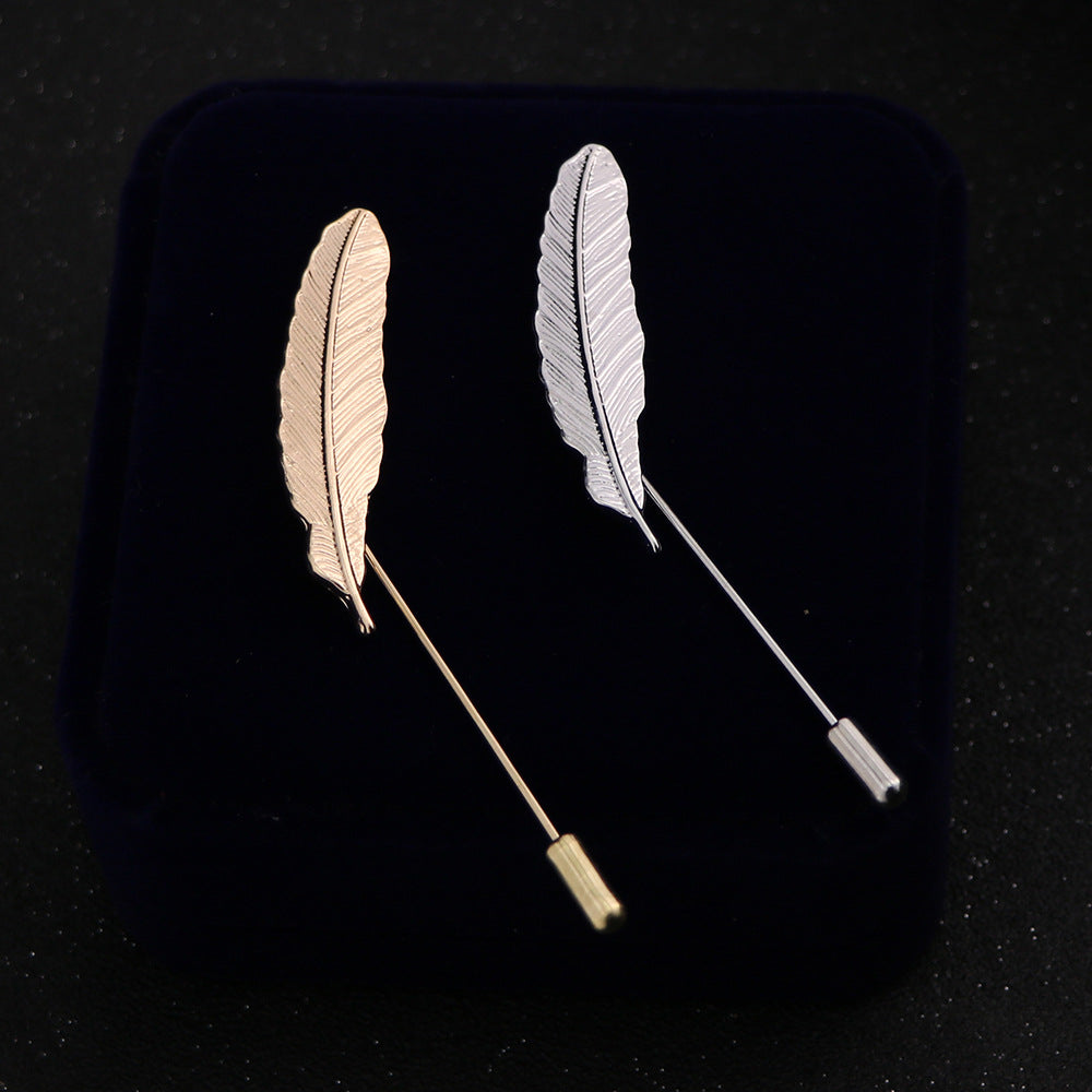 Gold feather lapel pin against a white background