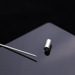 Silver feather lapel pin displayed on fabric
