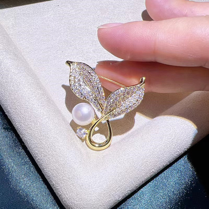 Gold leaf design of the brooch with pearl accents