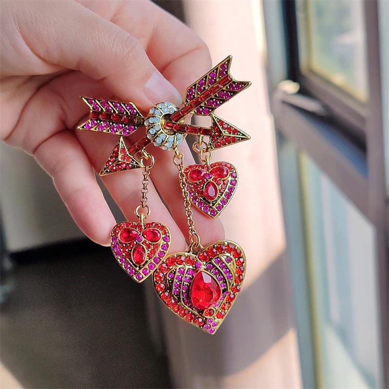 Red Cupid heart arrow pin displayed on fabric