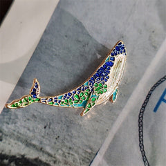 Unique whale and dolphin pin displayed on elegant fabric