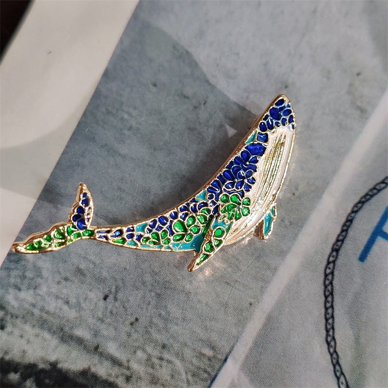 Unique whale and dolphin pin displayed on elegant fabric