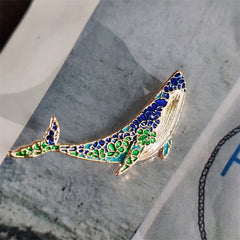 Unique whale and dolphin pin displayed on elegant fabric