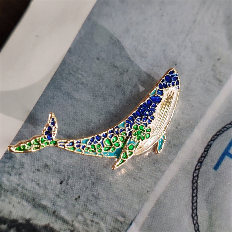 Unique whale and dolphin pin displayed on elegant fabric