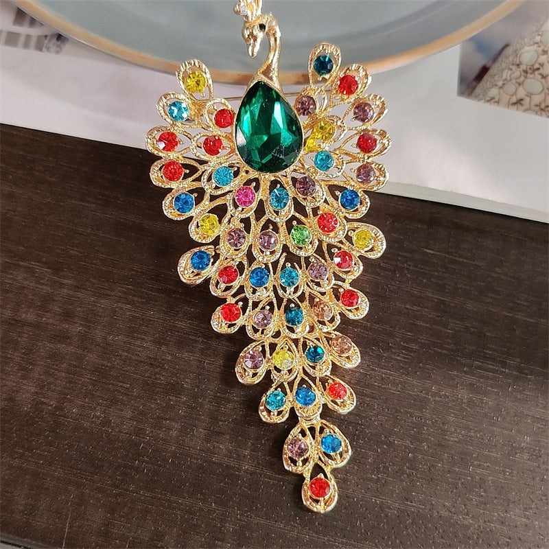 Vibrant peacock brooch in emerald gold