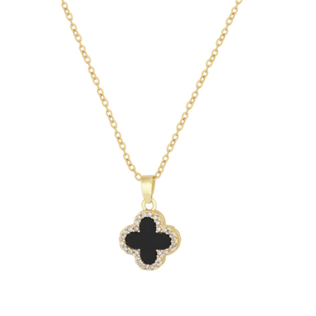 Four-leaf clover necklace lying on a marble surface