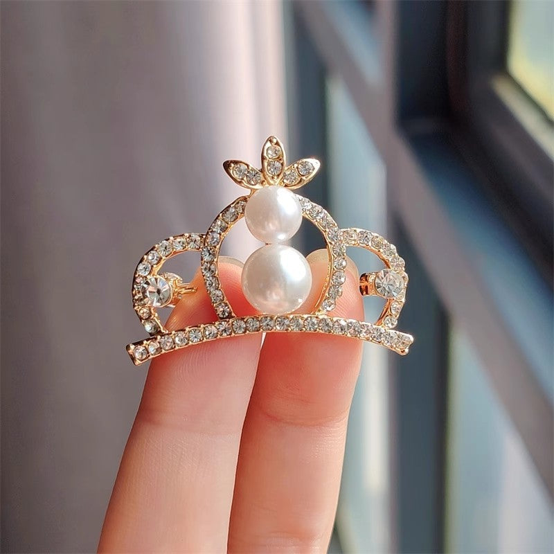 Silver crown brooch on black background