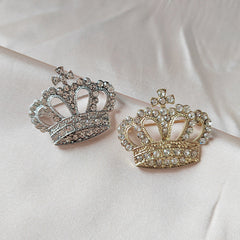 Silver crown brooch on black background